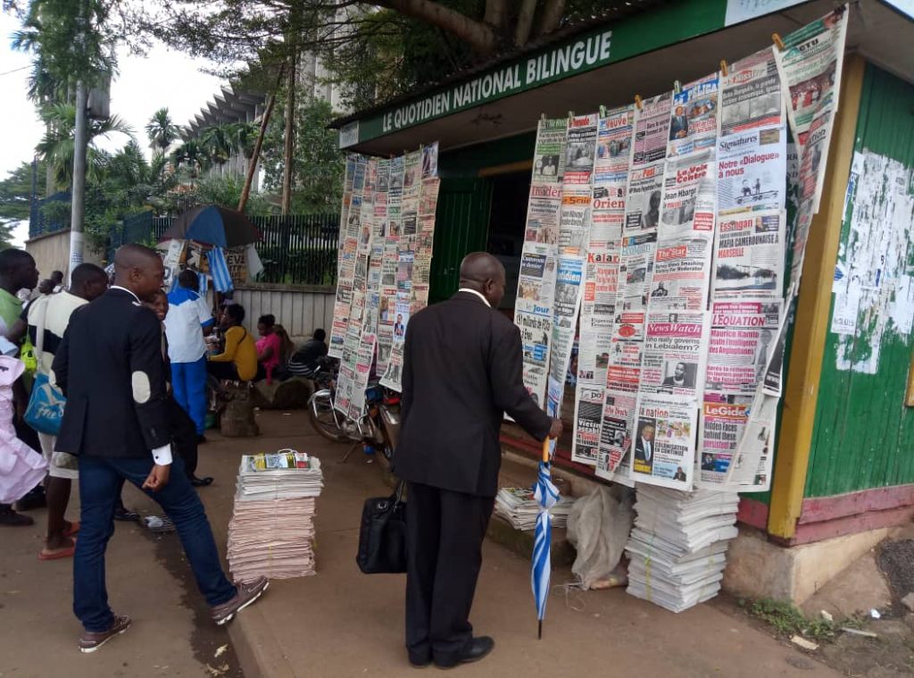 Some Cameroonians read newspaper headlines at a kiosk adjacent the Ministry of Finance in Yaounde.